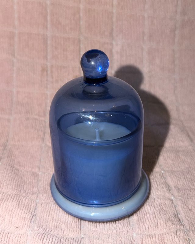 A small candle under a blue glass bell