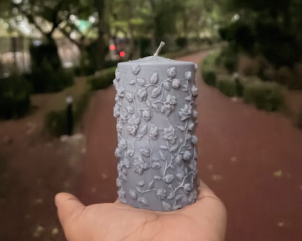 A floral pillar candle held in the hand