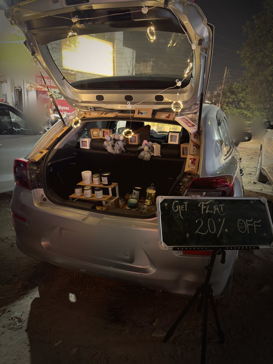 The open boot of a hatchback turned into a candle stall, strung with fairy lights