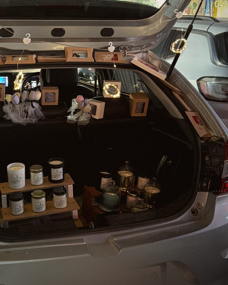 Candle jars arranged on a two-step wooden shelf inside the boot