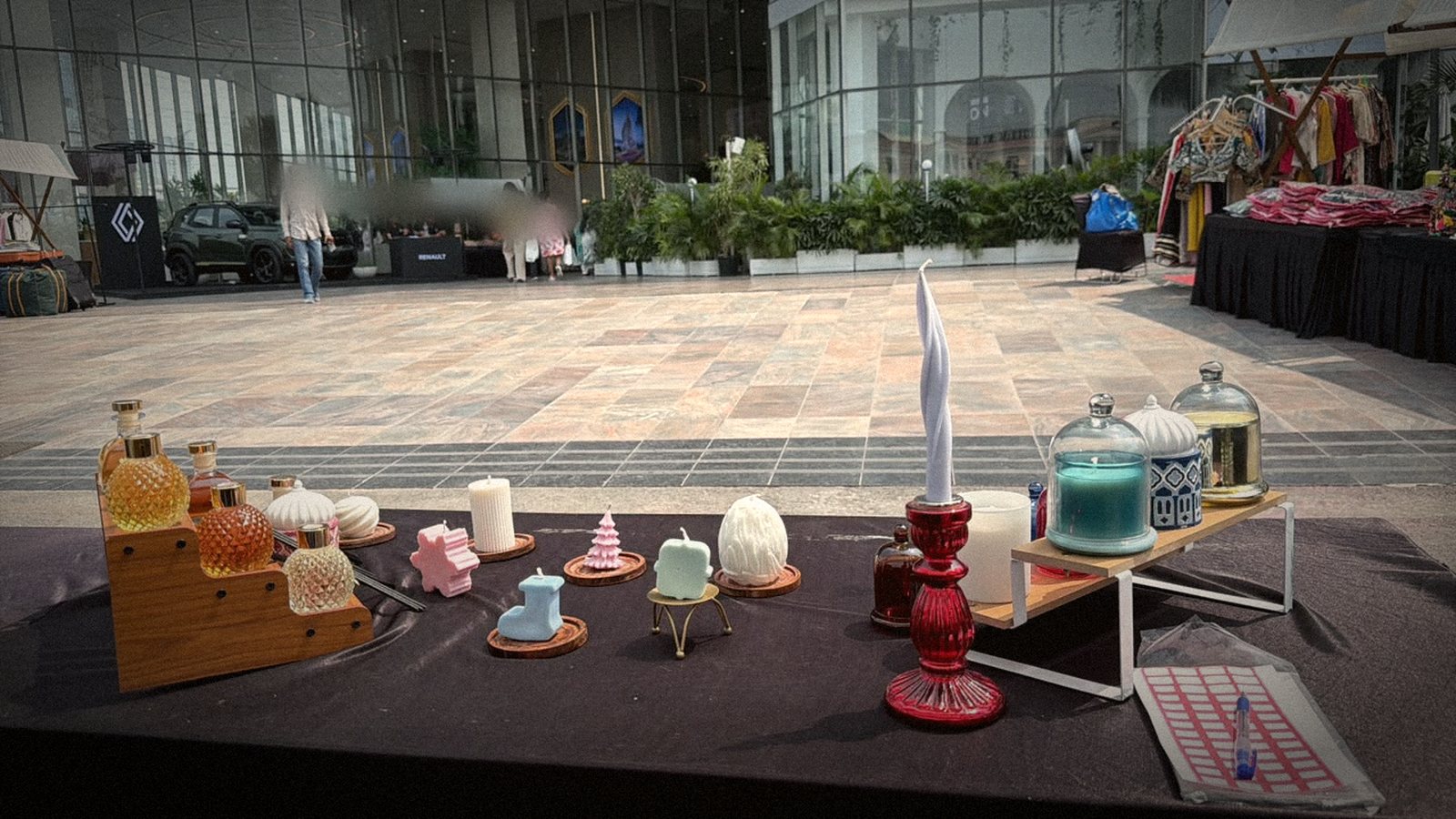 Small shaped candles and reed diffusers on the table, with the plaza behind