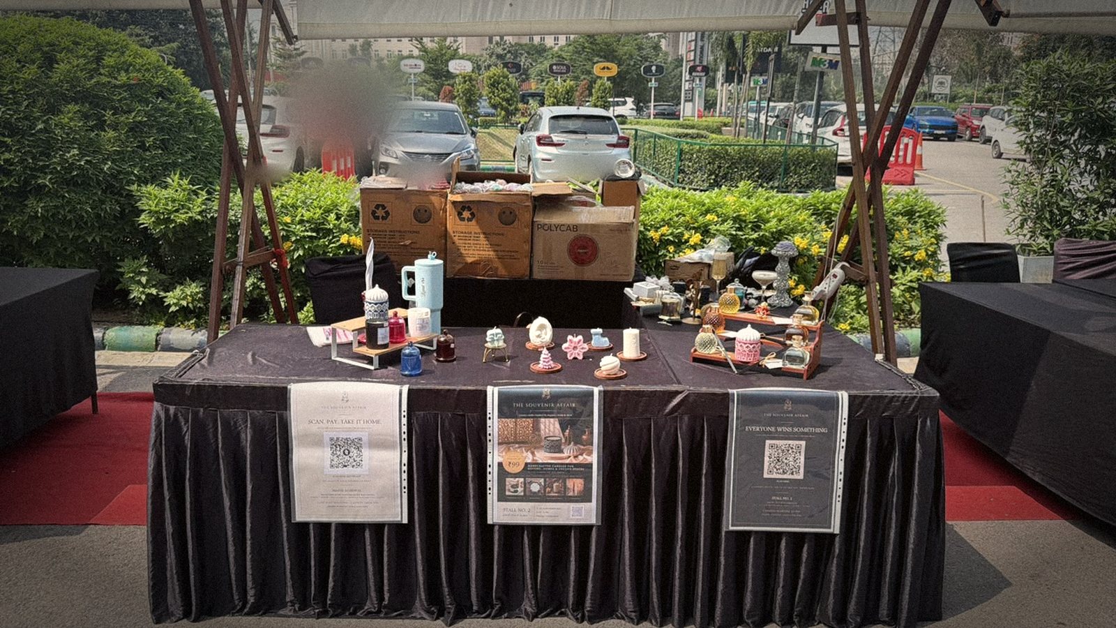 The stall table half dressed, open cartons behind it and three posters along the front